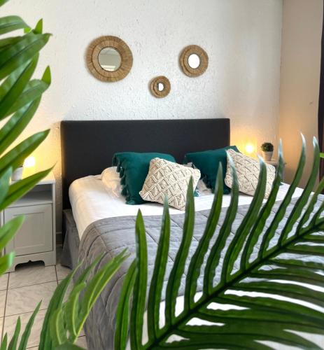 a bedroom with a bed with green pillows and a plant at La Maison Blanche in Sangatte