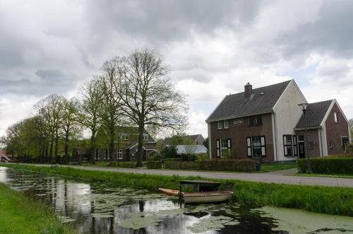 a house and a river with a boat in it at 4p chalet TOLVE met 4 fietsen vlakbij natuurgebieden Drents Friese Wold, Fochteloërveen en gevangenisdorp Veenhuizen in Oosterwolde