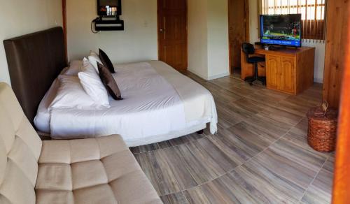 a bedroom with a bed and a television and a couch at Hotel Gran Boutique Sabana in Chía