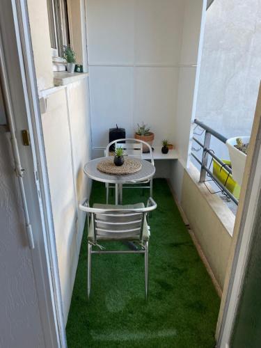 d'une petite table et de chaises sur un balcon avec de l'herbe verte. dans l'établissement Grand Studio 7 minutes de la Plage et Climatisé sur Juan Les Pins, à Antibes