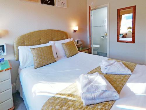 a bedroom with a large white bed with towels on it at Riviera Lodge Hotel in Torquay