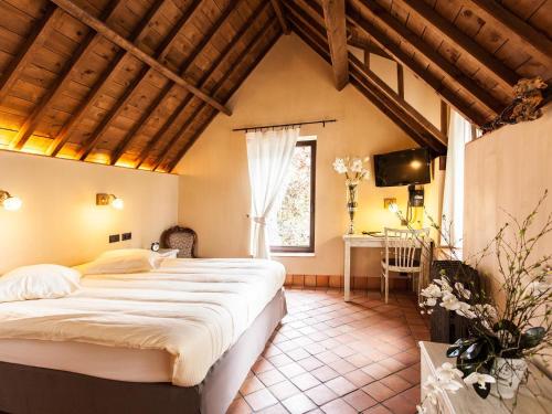 a bedroom with a large bed and a desk at Thermae Boetfort Hotel in Steenokkerzeel