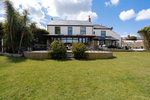 una gran casa blanca con un patio de césped en The Cedars, en Redruth