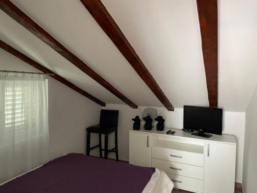- une chambre avec un lit et une télévision sur une commode dans l'établissement Bella Vacanza, à Njivice