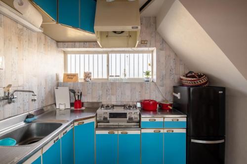 cocina con armarios azules y nevera negra en VILLENT KUJUKURI ARROW - Vacation STAY 32961v, en Kujukuri