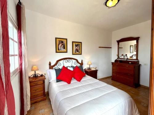 a bedroom with a white bed with red pillows at Casa María - Finca Medina in Alojera