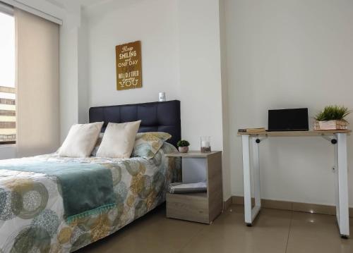 a bedroom with a bed and a desk with a laptop at Hermoso Apartamento Central in Pereira