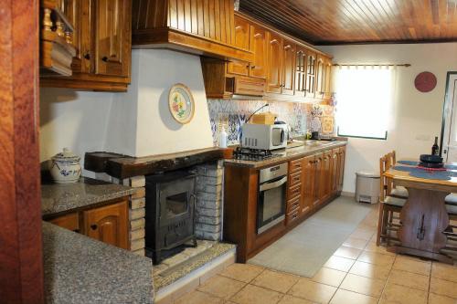 a kitchen with wooden cabinets and a stone fireplace at Casas D'Aldeia Arcos de Valdevez in Arcos de Valdevez
