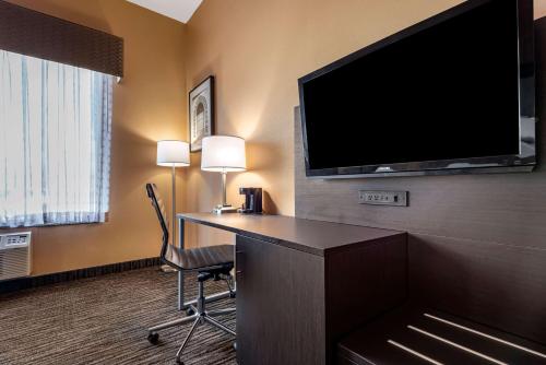 a hotel room with a desk and a flat screen tv at Best Western the Inn at the Fairgrounds in Syracuse