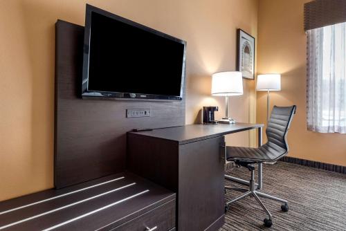 a hotel room with a desk and a television on a wall at Best Western the Inn at the Fairgrounds in Syracuse