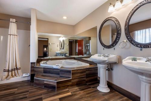 a bathroom with two sinks and a tub and mirrors at Best Western the Inn at the Fairgrounds in Syracuse