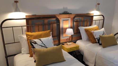 a room with two beds and a table with a lamp at LARANJEIRA das LOIRAS in Óbidos