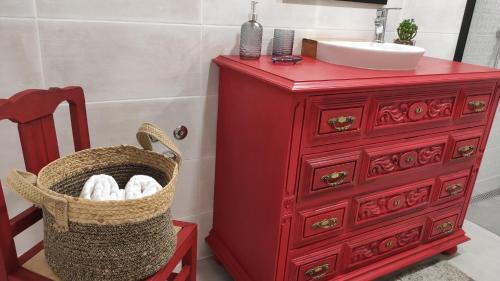 un tocador rojo con lavabo y una cesta de toallas en LARANJEIRA das LOIRAS, en Óbidos