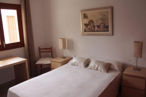 a bedroom with a white bed and a picture on the wall at Bonito Chalet en Sa Ràpita in Sa Ràpita