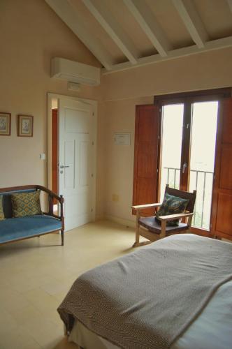 a bedroom with a bed and a chair and a window at Casa Rural El Vihuelo in El Bosque