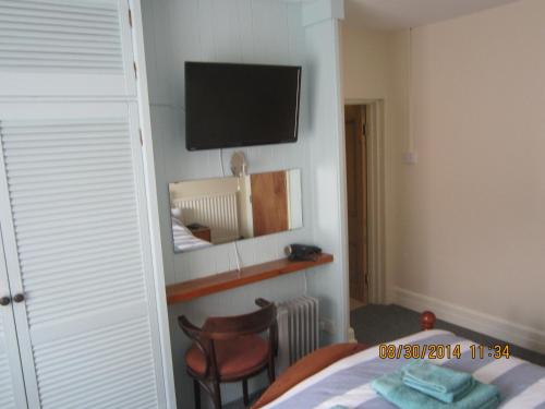 a bedroom with a bed and a television on the wall at Queen Mary Inn in Poole