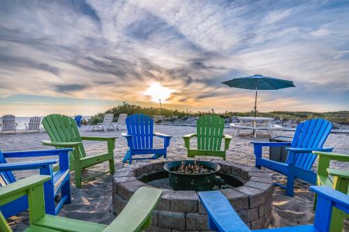 a group of chairs sitting around a fire pit on the beach at Sandbars Inn in North Truro