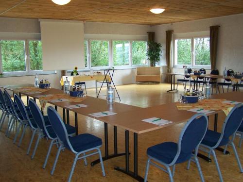 a room with a large table with chairs and windows at Landhotel Klingerhof in Hösbach