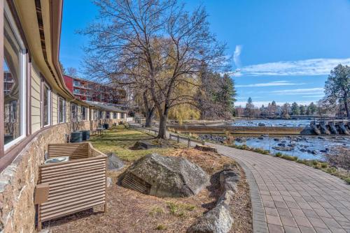 a building with a walkway next to a river at Bend Riverside Condos Near Downtown Bend in Bend