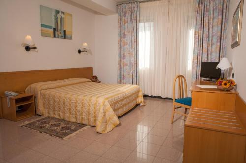 アルベロベッロにあるホテル アストリアのベッドとテレビが備わるホテルルームです。