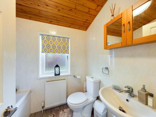 a bathroom with a toilet and a sink and a window at 3 Bedroom Lakeview Lodge - Ensuite & Balcony Deck in Carnforth