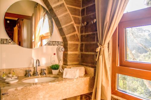 uma casa de banho com um lavatório, um espelho e uma janela em Pousada Castello Benvenutti em Bento Gonçalves