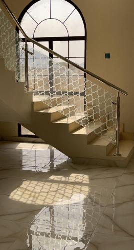 a staircase with a metal railing in front of a window at Al Ghadeer Maison Masfout in Sharīyah