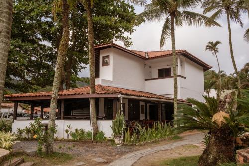 ein Haus mit Palmen davor in der Unterkunft Barequeçaba Praia Hotel in Barequeçaba