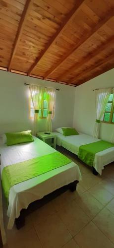 two beds in a room with green sheets at Hotel Campestre Pueblo Bello in Armenia