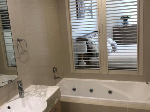 a bathroom with a sink and a dog looking out the window at Grand Mercure Allegra Hervey Bay in Hervey Bay
