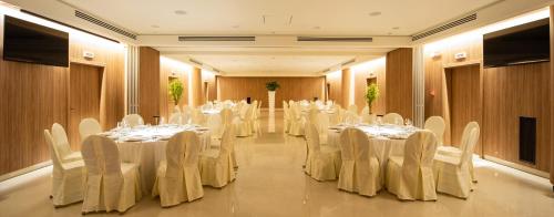 a banquet hall with white tables and white chairs at Gold Tower Lifestyle Hotel in Naples