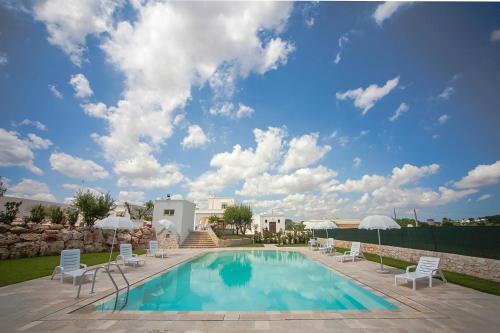 a swimming pool with white chairs and a blue sky at Coppola di Seta in Locorotondo