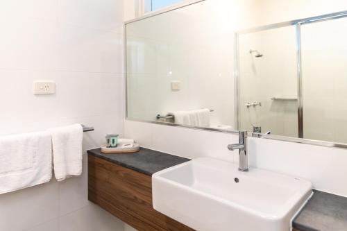 a white bathroom with a sink and a mirror at Salisbury Hotel Motel in Brisbane