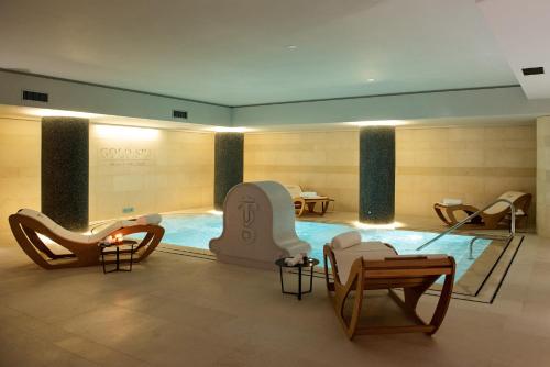 a room with a swimming pool with chairs and tables at Gold Tower Lifestyle Hotel in Naples