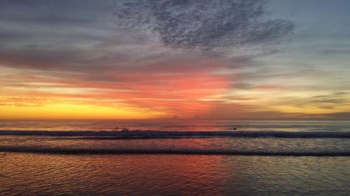 a sunset on the beach with people in the water at Outrigger Burleigh in Gold Coast