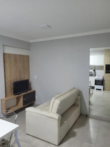 a living room with a couch and a tv at Novo Lar Garopaba1 in Garopaba