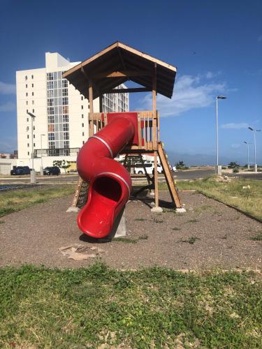 a playground with a red slide and a wooden bench at Bayfront Villa & Apartment in Portmore