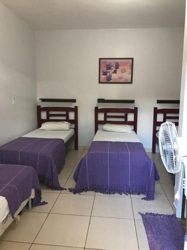 two beds in a room with purple sheets at Recanto do Carreiro in Trindade