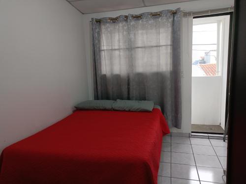 a red bed in a room with a window at Pinares de Santa monica 6HB in Nueva San Salvador