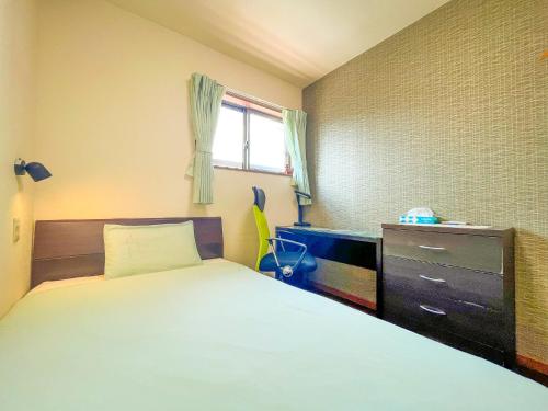 a bedroom with a bed and a dresser and a window at B&B 4 Rooms in Naha