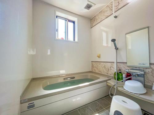 a bathroom with a tub with a toilet and a sink at B&B 4 Rooms in Naha