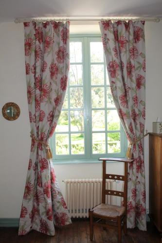 a window with curtains and a chair in a room at Chambres d'Hôtes Belle Vallee in Domfront
