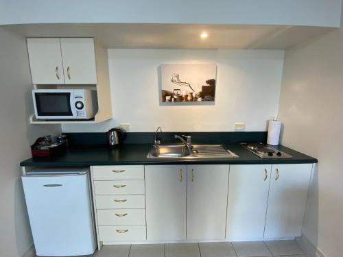 a small kitchen with a sink and a microwave at Motel On York in Dunedin
