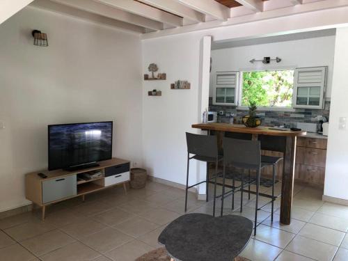 ein Wohnzimmer mit einem Tisch und einem TV in der Unterkunft Villa Fleur de Lys in Sainte-Anne