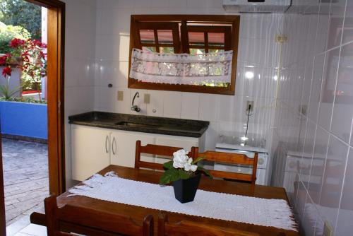 eine Küche mit einem Tisch und einer Blumenvase darauf in der Unterkunft Pousada Tempo Rei in Boicucanga