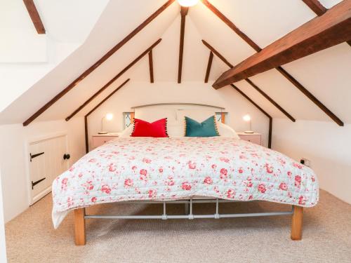 a bedroom with a large bed with red and green pillows at Poppy Cottage in Tiverton