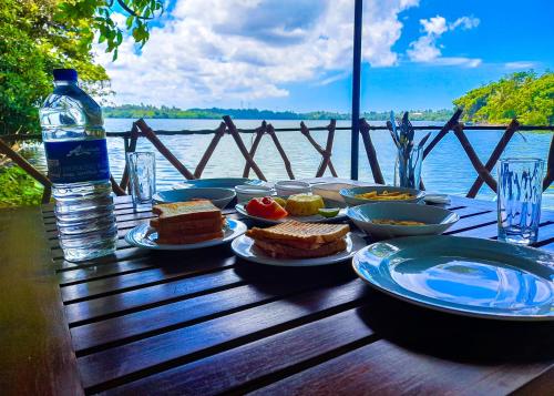 a table with plates of food and a bottle of water at Scenery River Star Hotel in Hikkaduwa