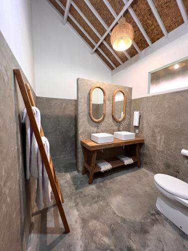 a bathroom with two sinks and two mirrors at Eden Eco Resort in Gili Trawangan