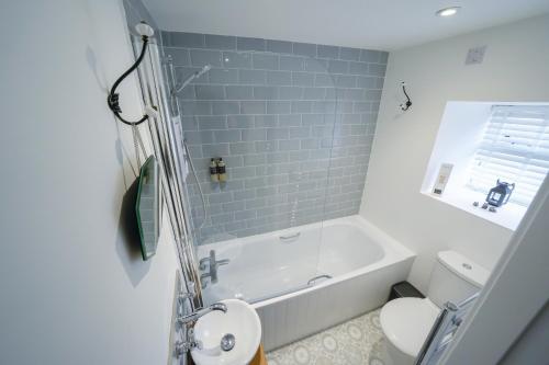 a white bathroom with a tub and a toilet at The Wee House by the Sea in Balintore