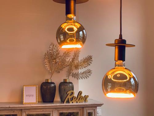 three pendant lights hanging above a table with vases at Vakantievilla Leonie in Lo-Reninge